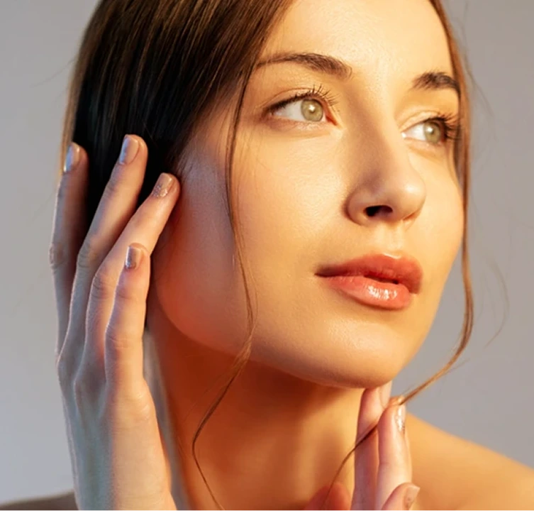 Woman touching her face, displaying smooth, glowing skin