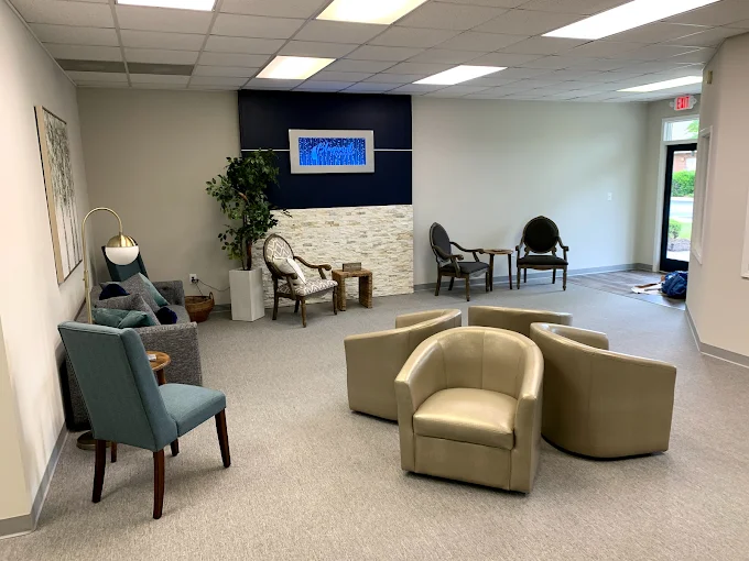 Open waiting area with comfortable seating, stone feature wall, plants, and bright lighting