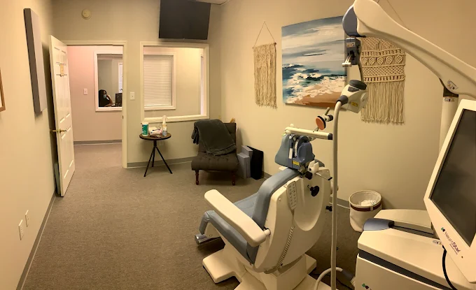 TMS clinic treatment room with device, waiting chair, monitor display, and calming d&eacute;cor