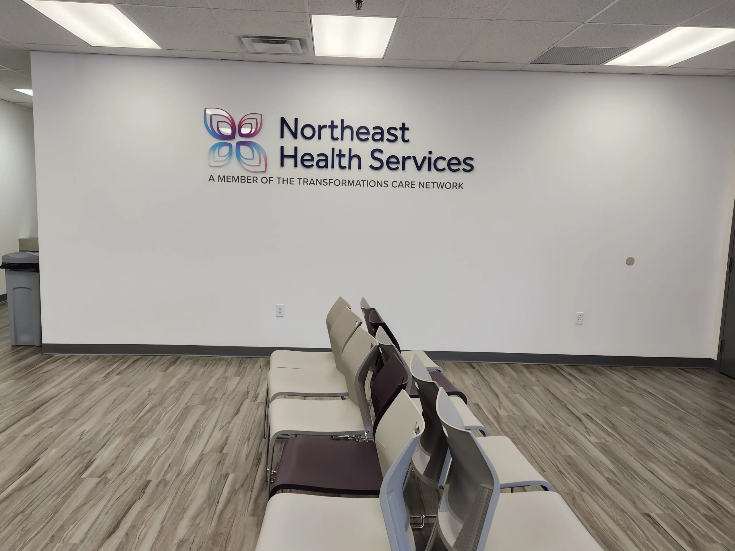Northeast Health Services logo and text on waiting room wall with seating below