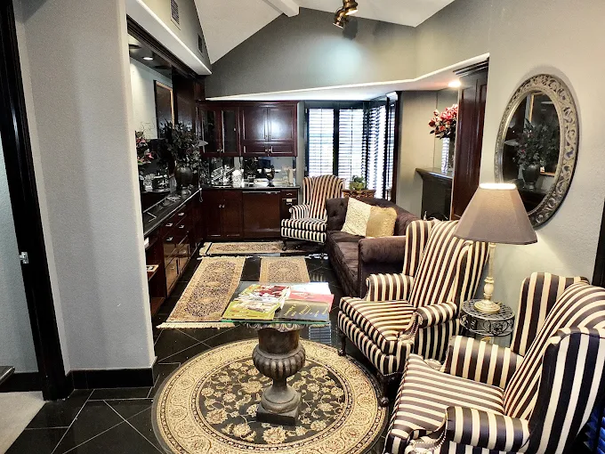 Elegant waiting room with striped chairs, dark wood cabinetry, decorative urn, and patterned area rug
