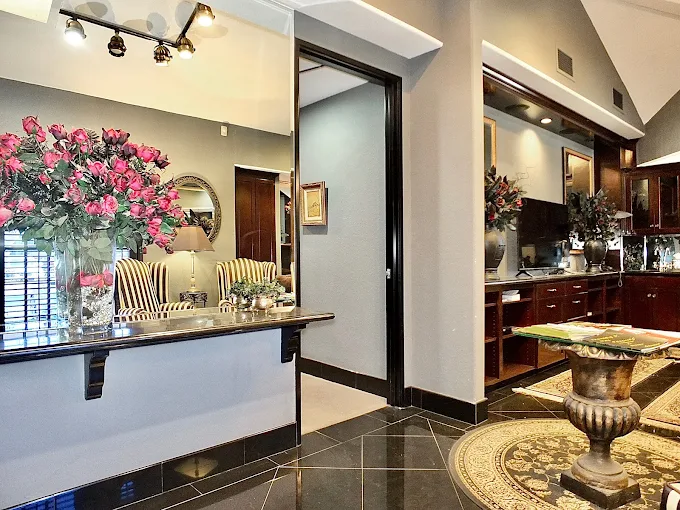 Clinical reception area with pink floral arrangement, dark wood desk, and framed mirror