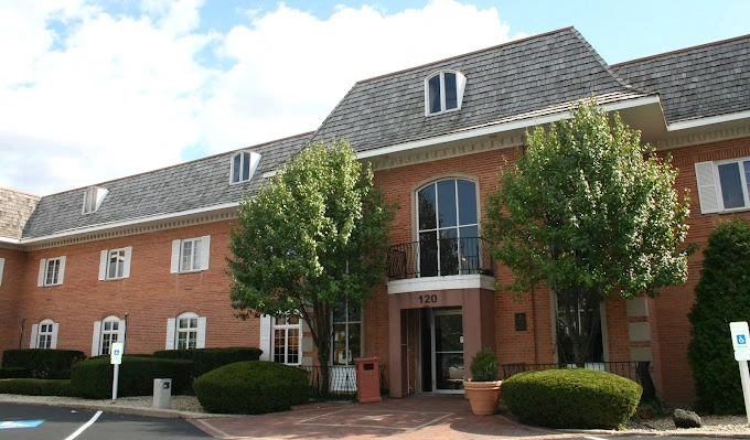 Brick medical office building with address 120, manicured hedges, and entrance doors