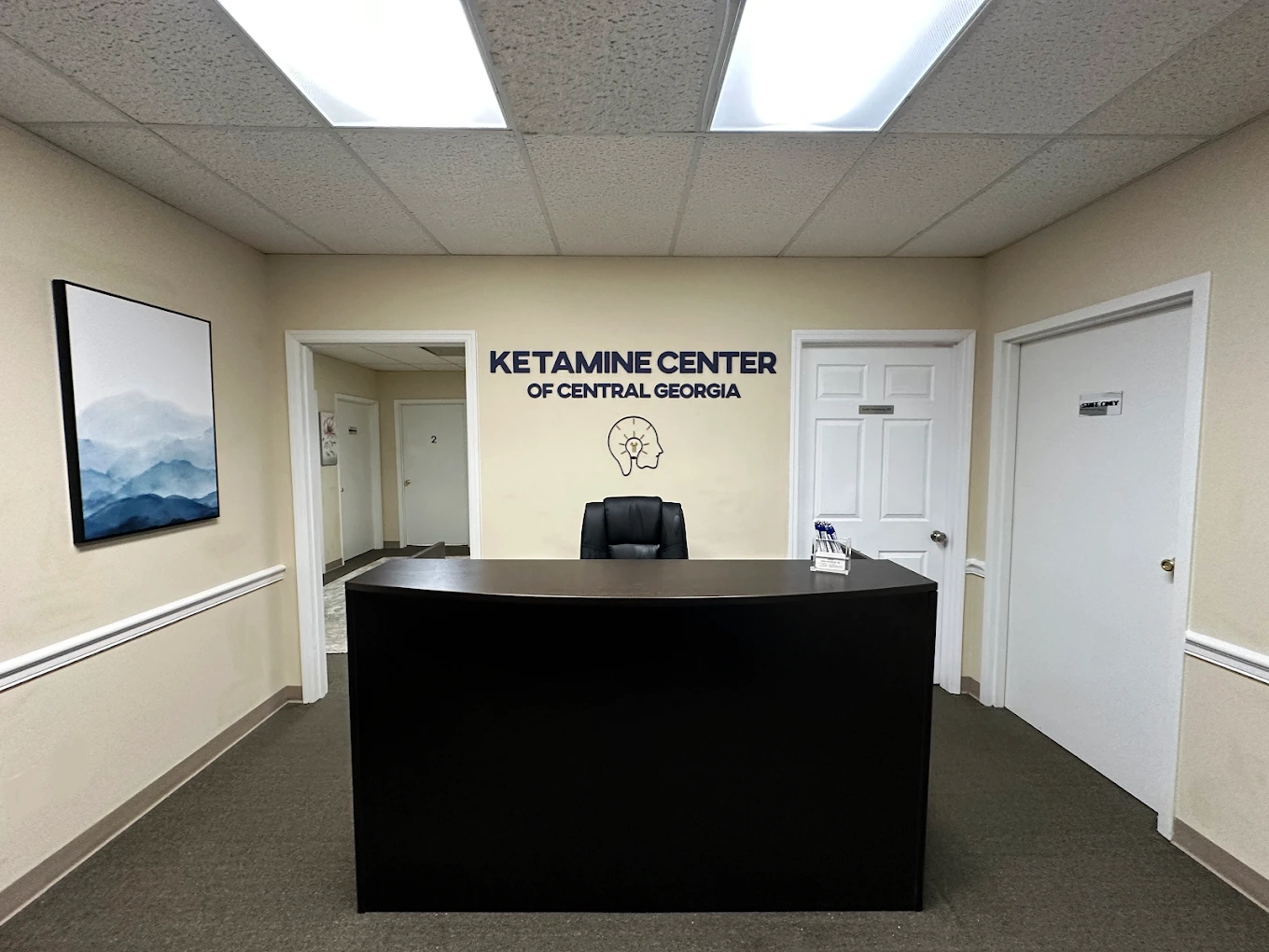 Ketamine Center of Central Georgia reception desk with logo and head icon on wall, mountain landscape artwork visible