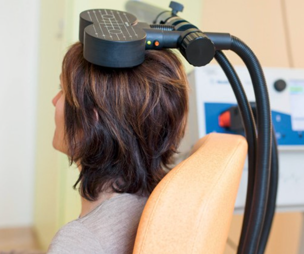 Patient receiving TMS therapy with magnetic coil positioned on scalp