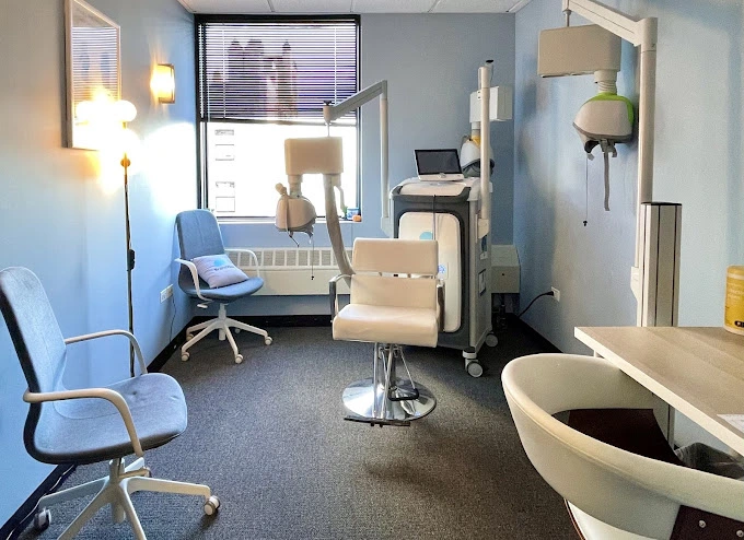 Medical treatment room with beige chair, blue seating area, and equipment on right side