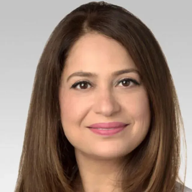 Professional headshot of a woman with long brown hair and pink lipstick