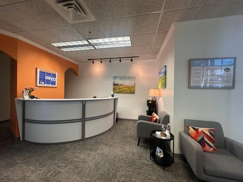 TMS clinic waiting room with curved reception desk, orange accent wall, and seating area