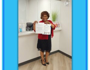 Woman in red shirt holding open educational materials at TMS therapy clinic reception desk