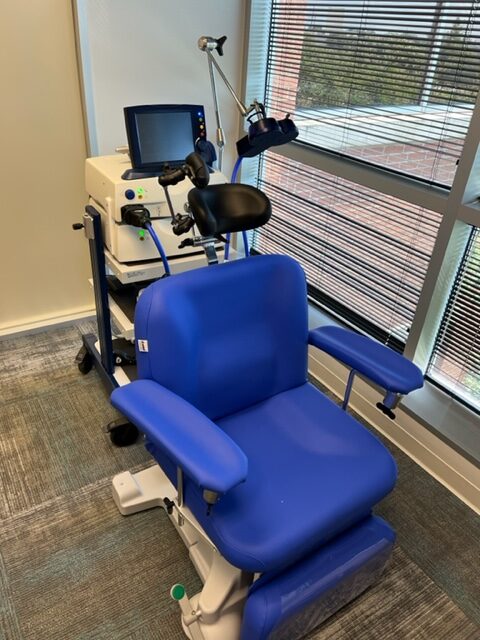 TMS treatment chair in blue with control panel and monitor mounted on white equipment cart