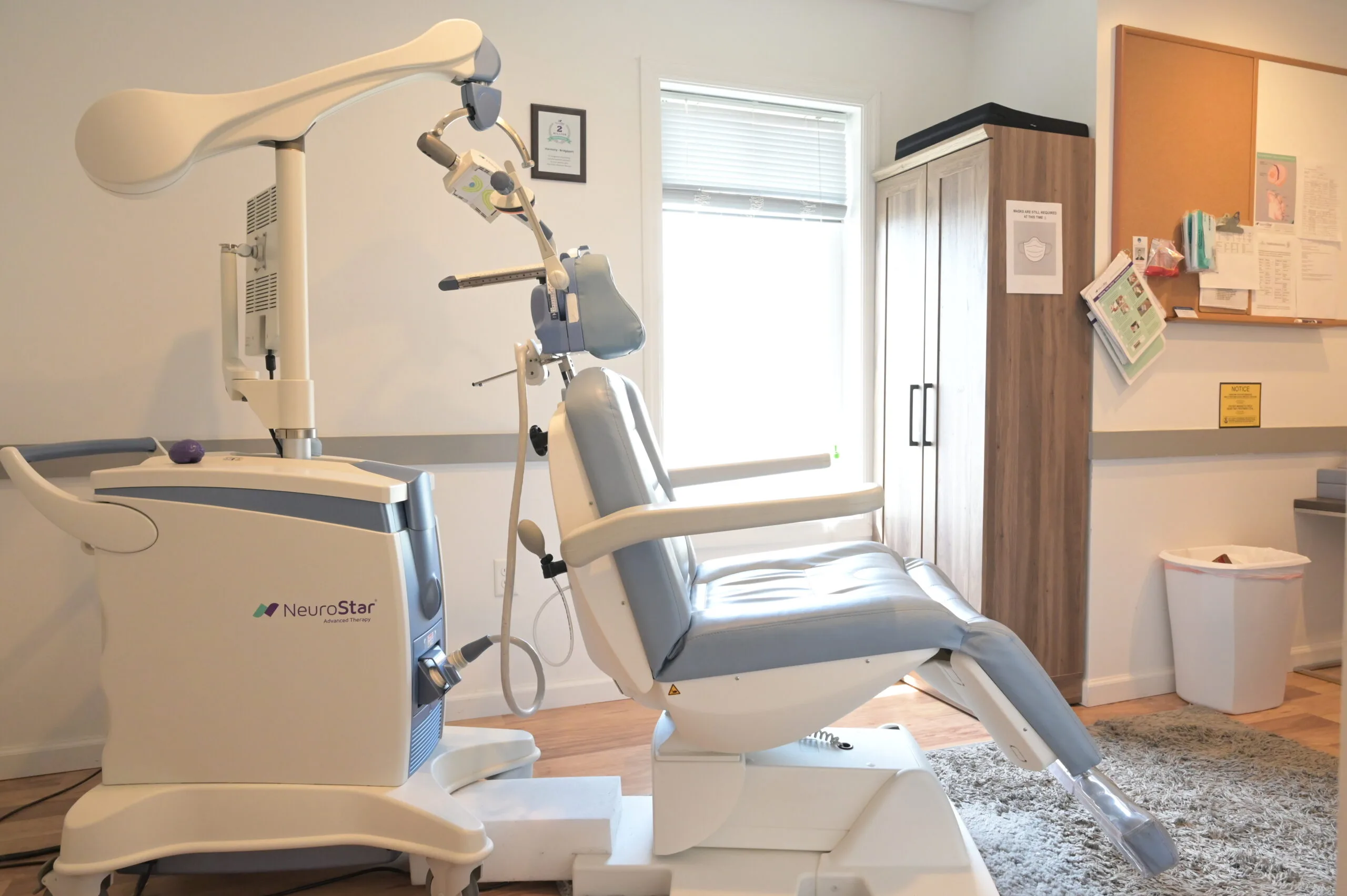 NeuroStar TMS treatment chair with overhead magnetic coil device in clinical room