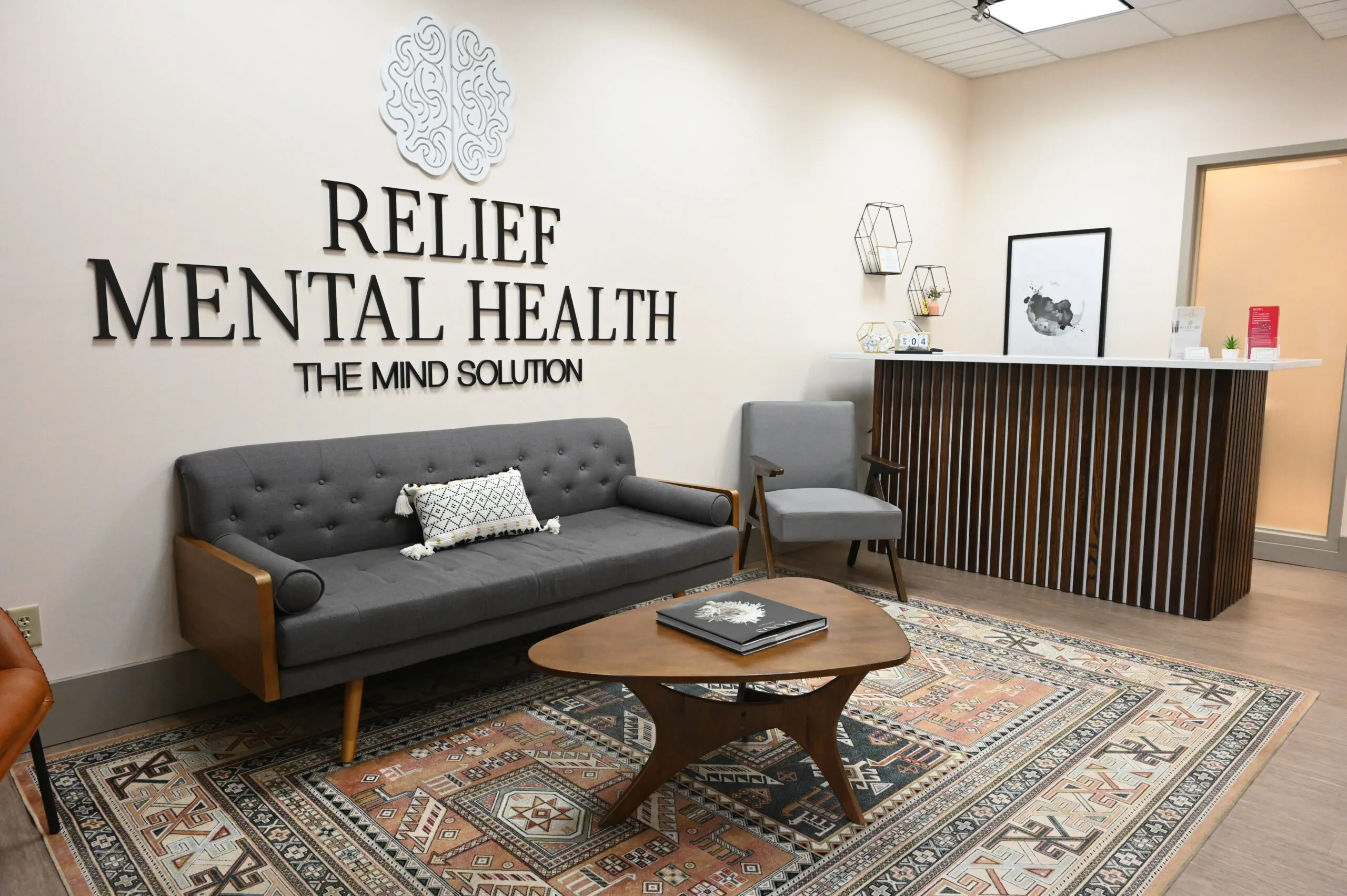 Relief Mental Health reception area with logo and tagline "The Mind Solution" above gray sofa and round wooden table