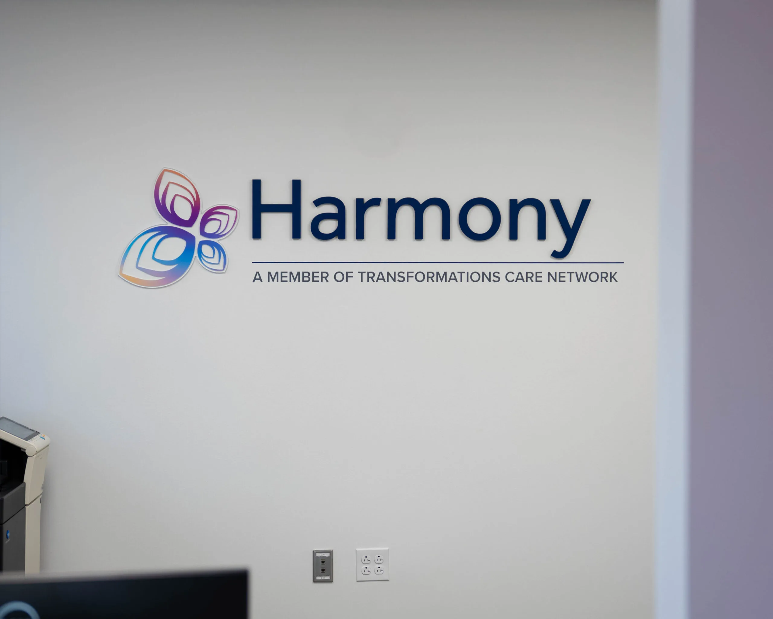 Harmony logo with text 'A Member of Transformations Care Network' on office wall