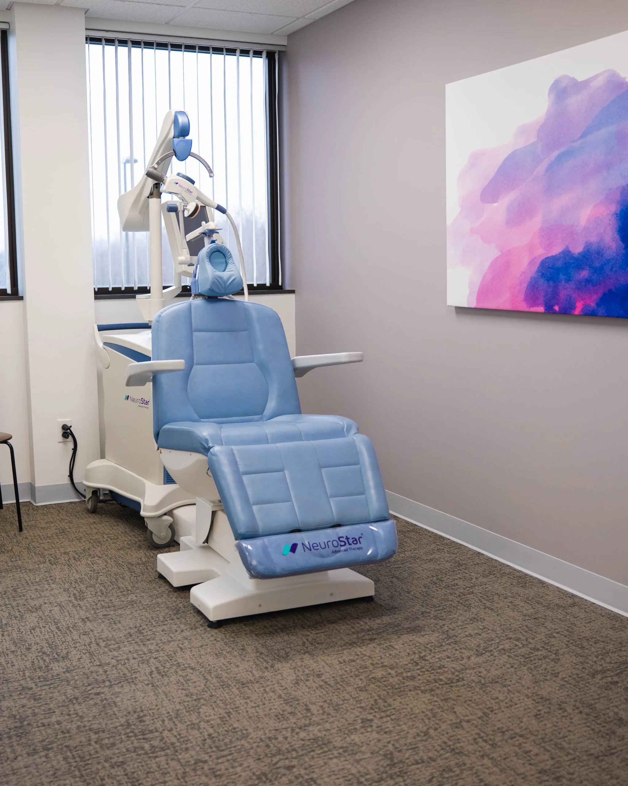 NeuroStar TMS therapy chair with blue cushioning and articulated treatment arm in clinical room