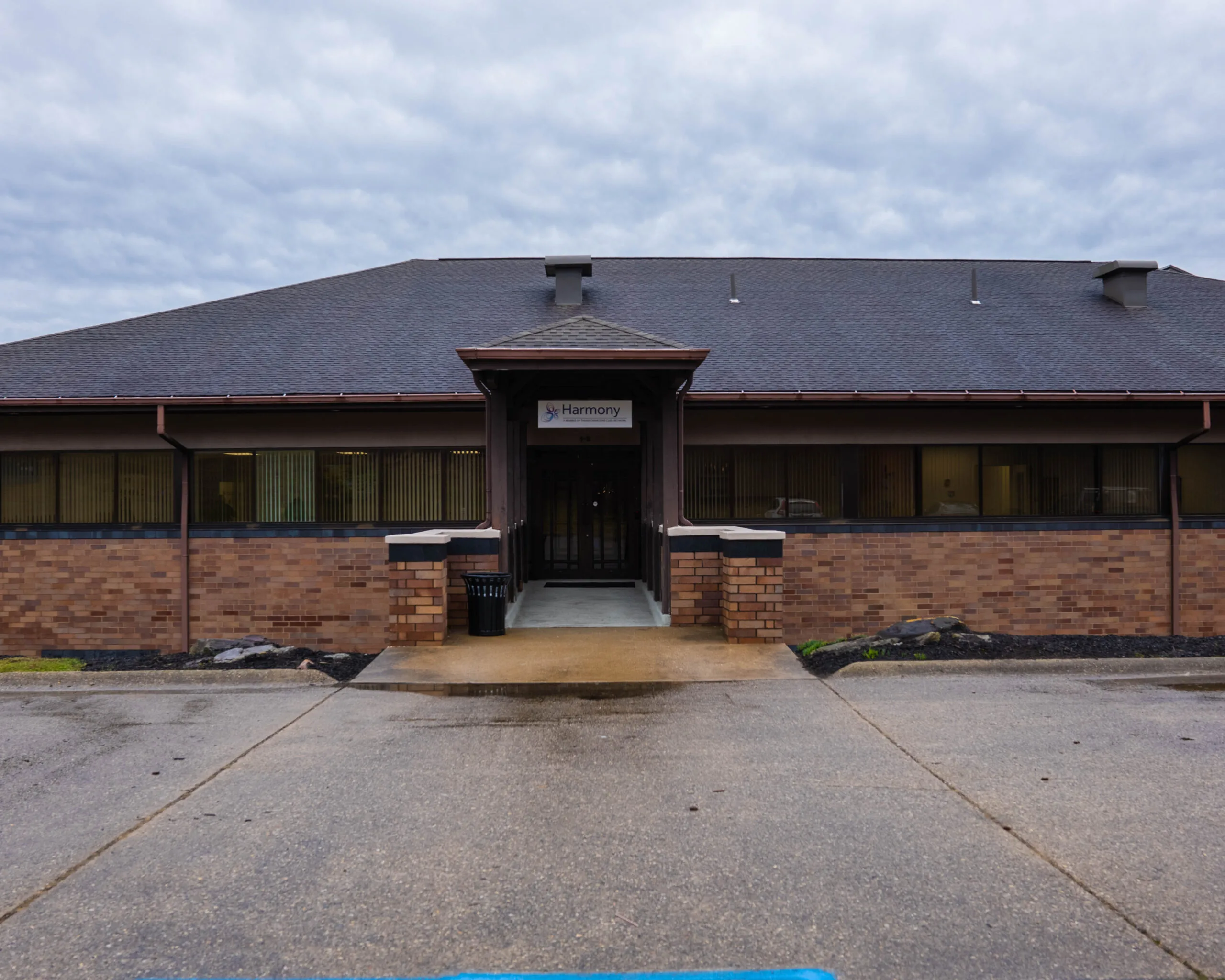 Harmony TMS therapy clinic entrance, brick and metal building with dark roof and covered entrance
