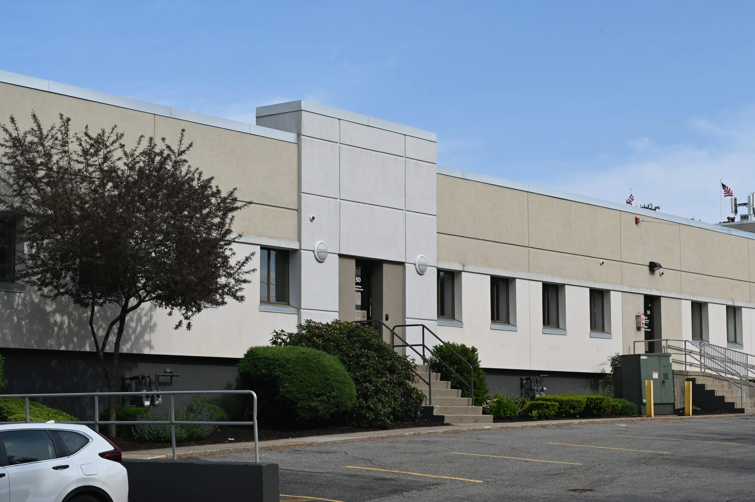 Modern single-story medical office building with beige and white exterior, landscaping, and parking lot