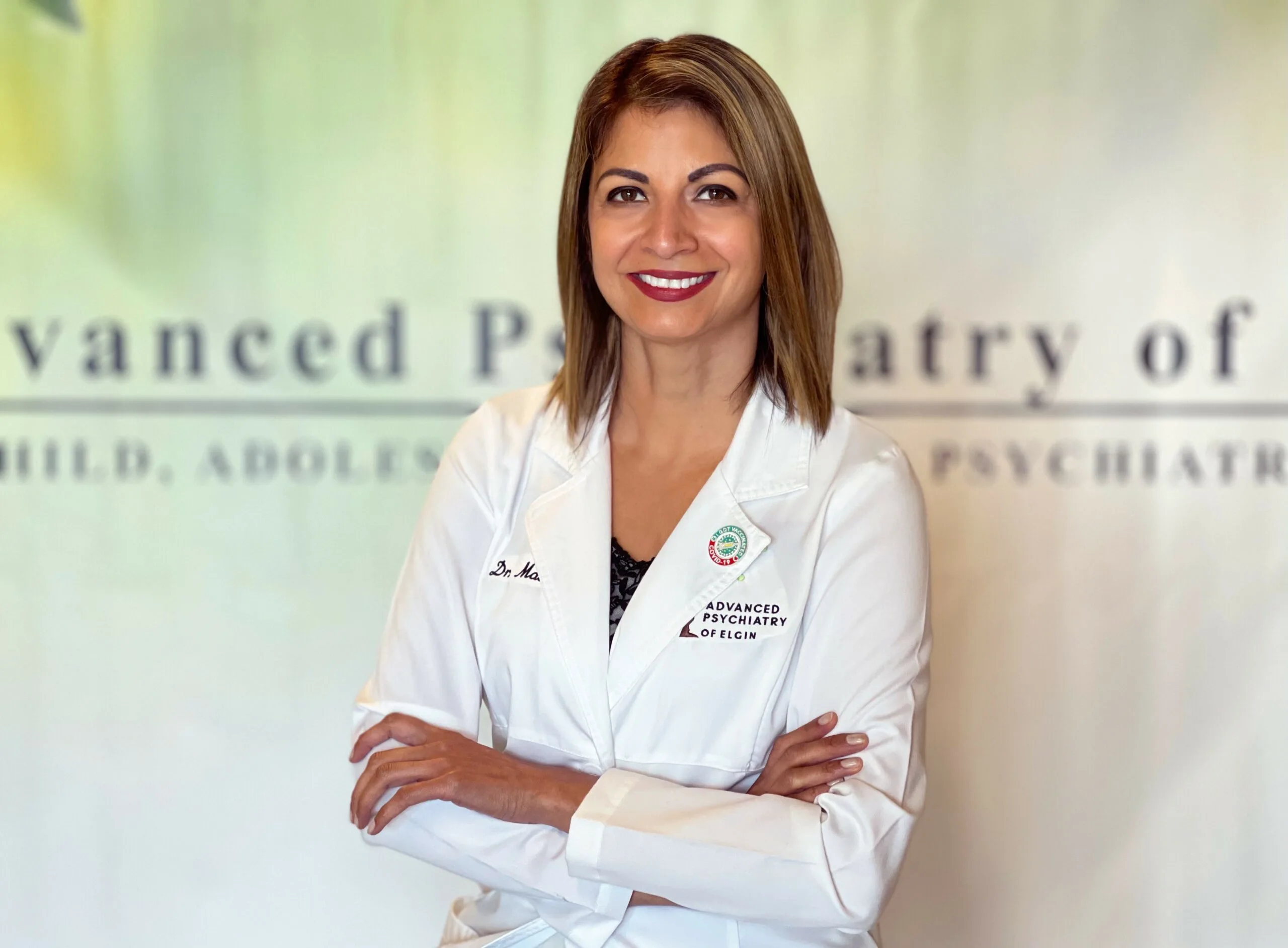 Dr. Malik in white coat with arms crossed, Advanced Psychiatry of Elgin logo visible
