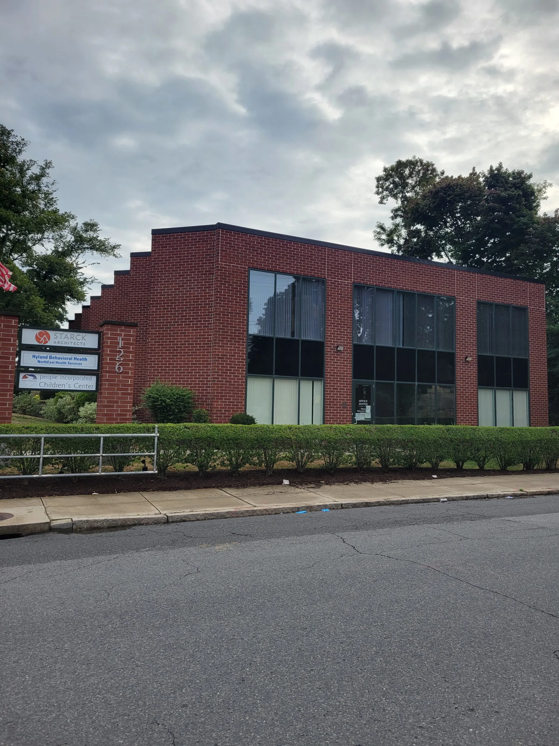 Red brick single-story medical office building with large windows and business signage on exterior