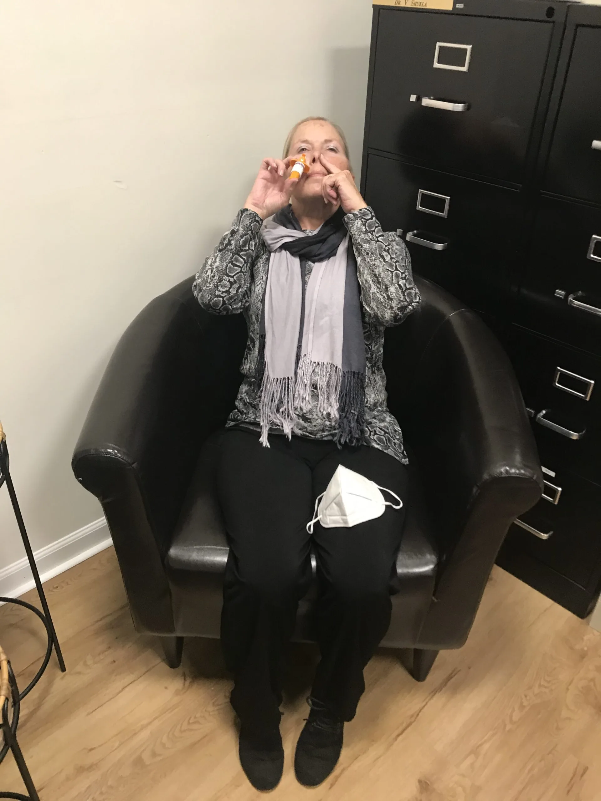 Patient applying sunscreen roller to face while seated in office