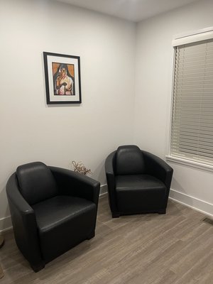 Quiet room with two black leather armchairs and framed religious artwork on wall