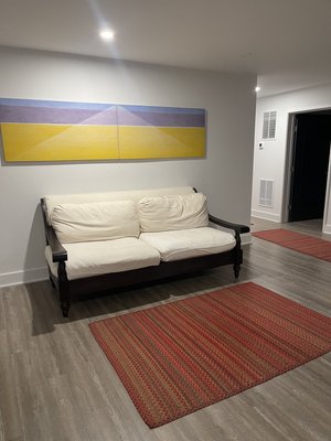 Clinic waiting area with cream-colored futon sofa, red patterned rug, and blue-and-yellow abstract wall art