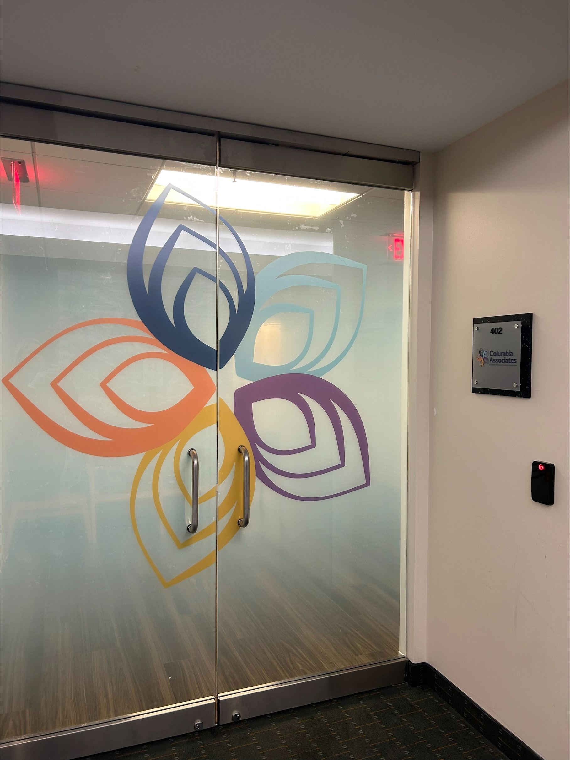 Glass office door with Columbia Associates colorful leaf logo in blue, orange, yellow, and purple