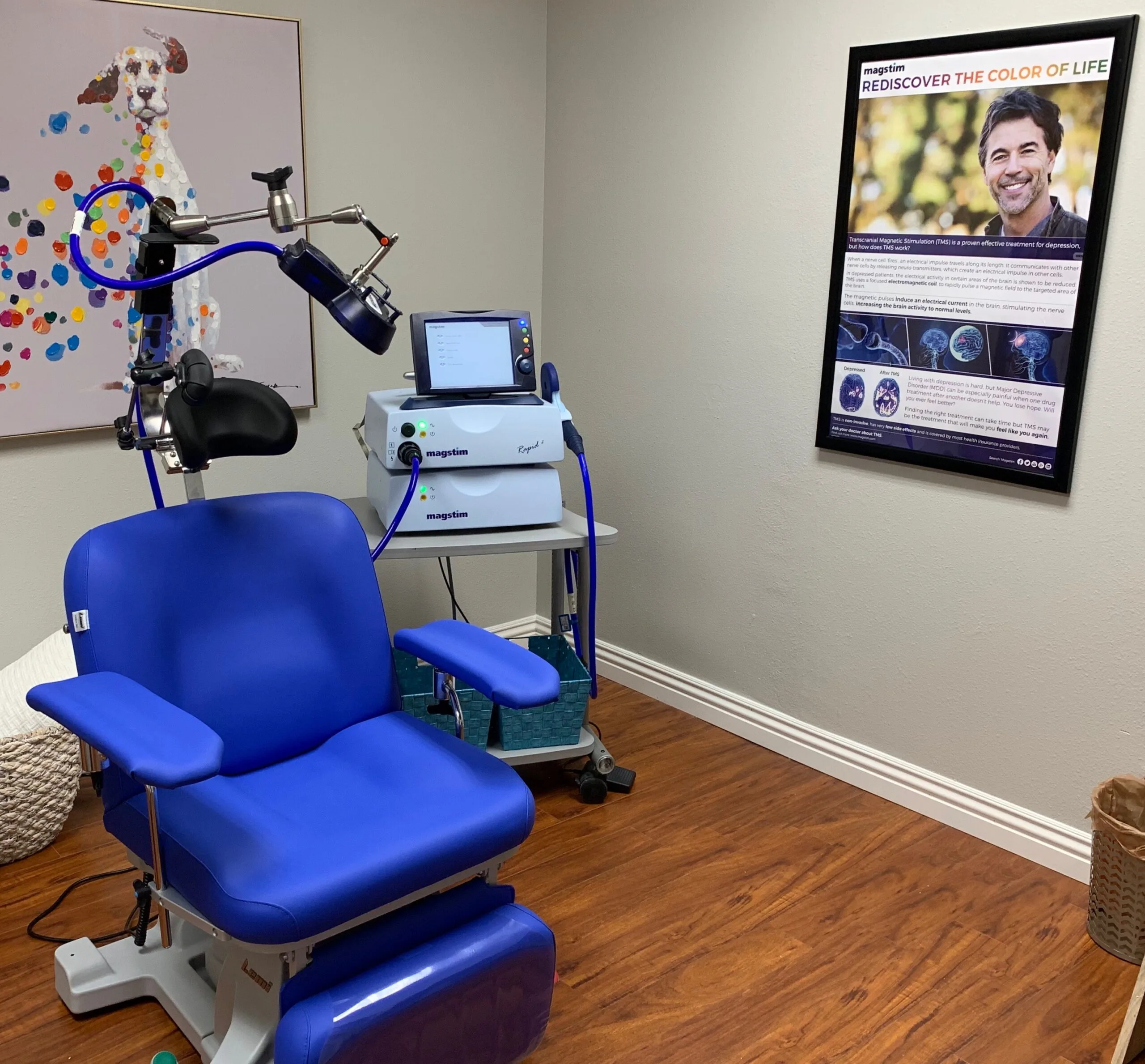 Blue TMS treatment chair with overhead magnetic coil device and control monitor in clinical room