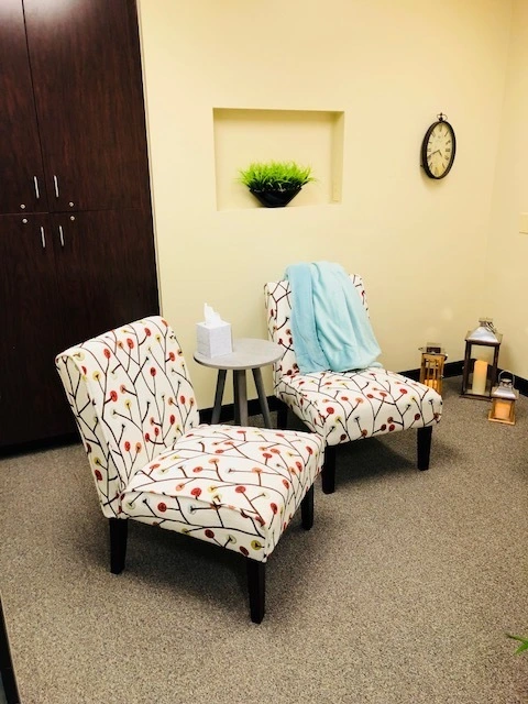 TMS treatment room with two patterned chairs, small side table, and decorative niche in wall