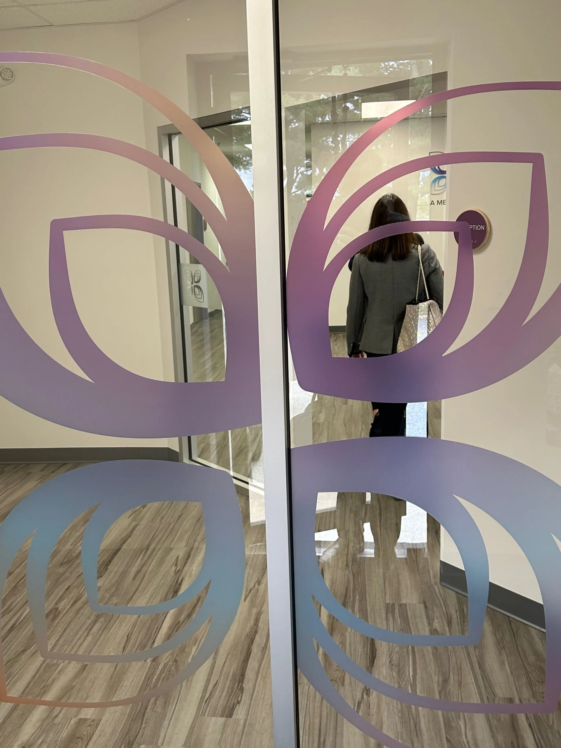 Person entering glass door with purple and blue wavy logo design