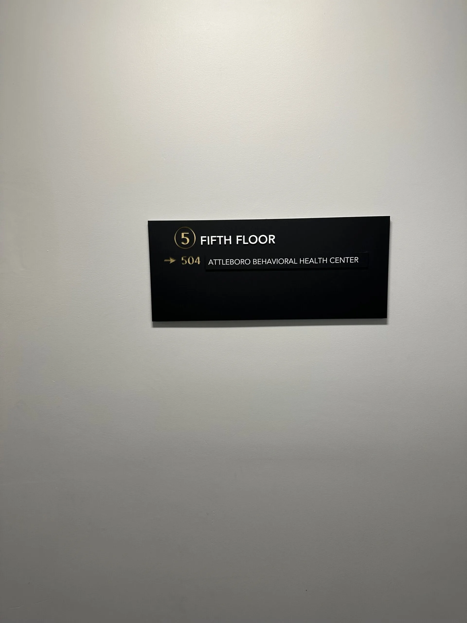 Black floor sign reading 'FIFTH FLOOR 504 ATTLEBORO BEHAVIORAL HEALTH CENTER'