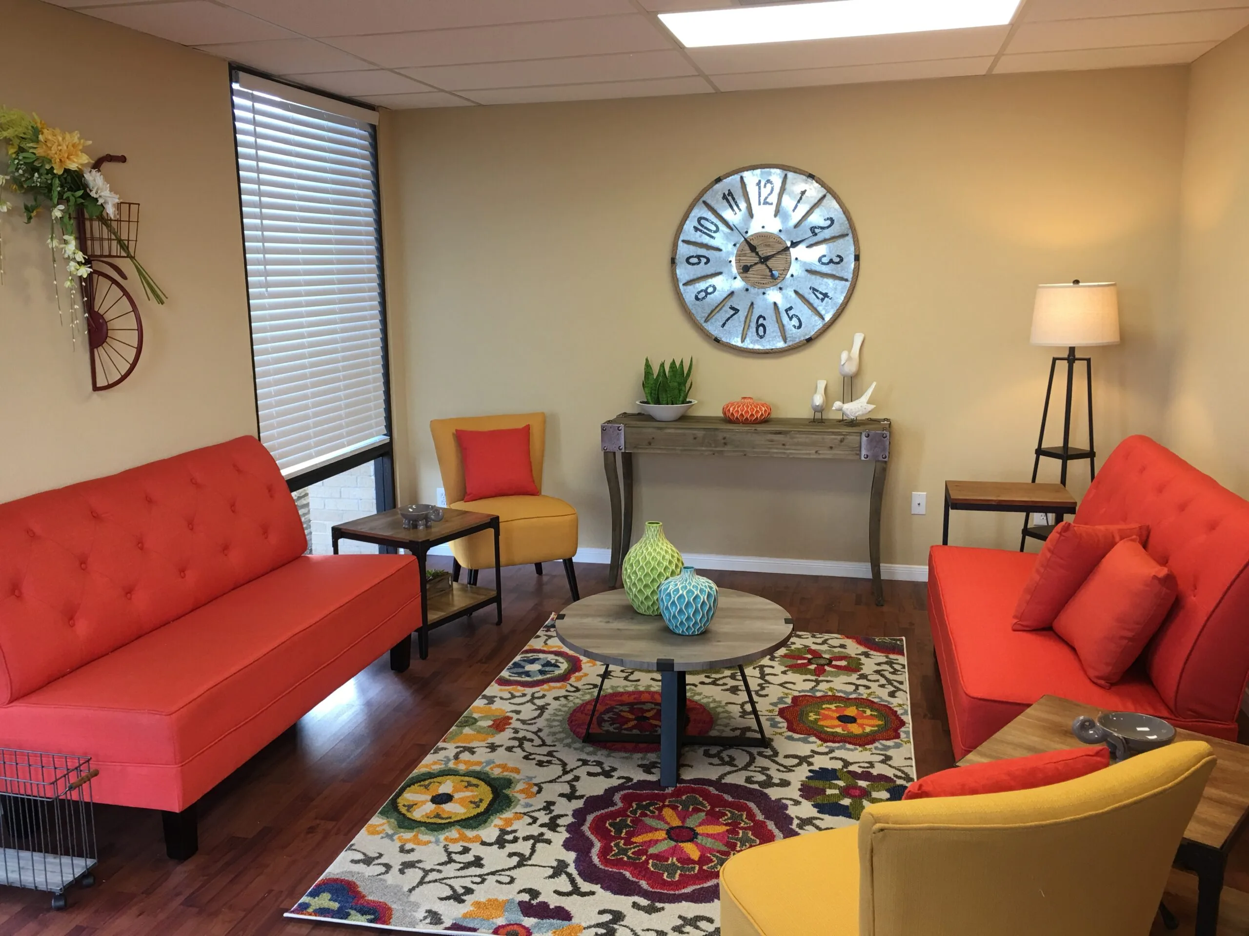 Mopac office reception room with red sofas, yellow chair, and round blue clock