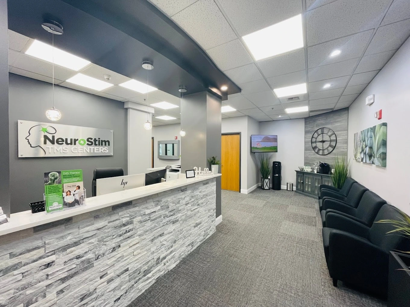 NeuroStim TMS Centers reception area with front desk, logo signage, and modern waiting space with plants