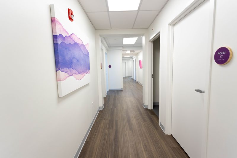 Hallway with purple watercolor artwork, room 17 door marker, and multiple treatment room doors