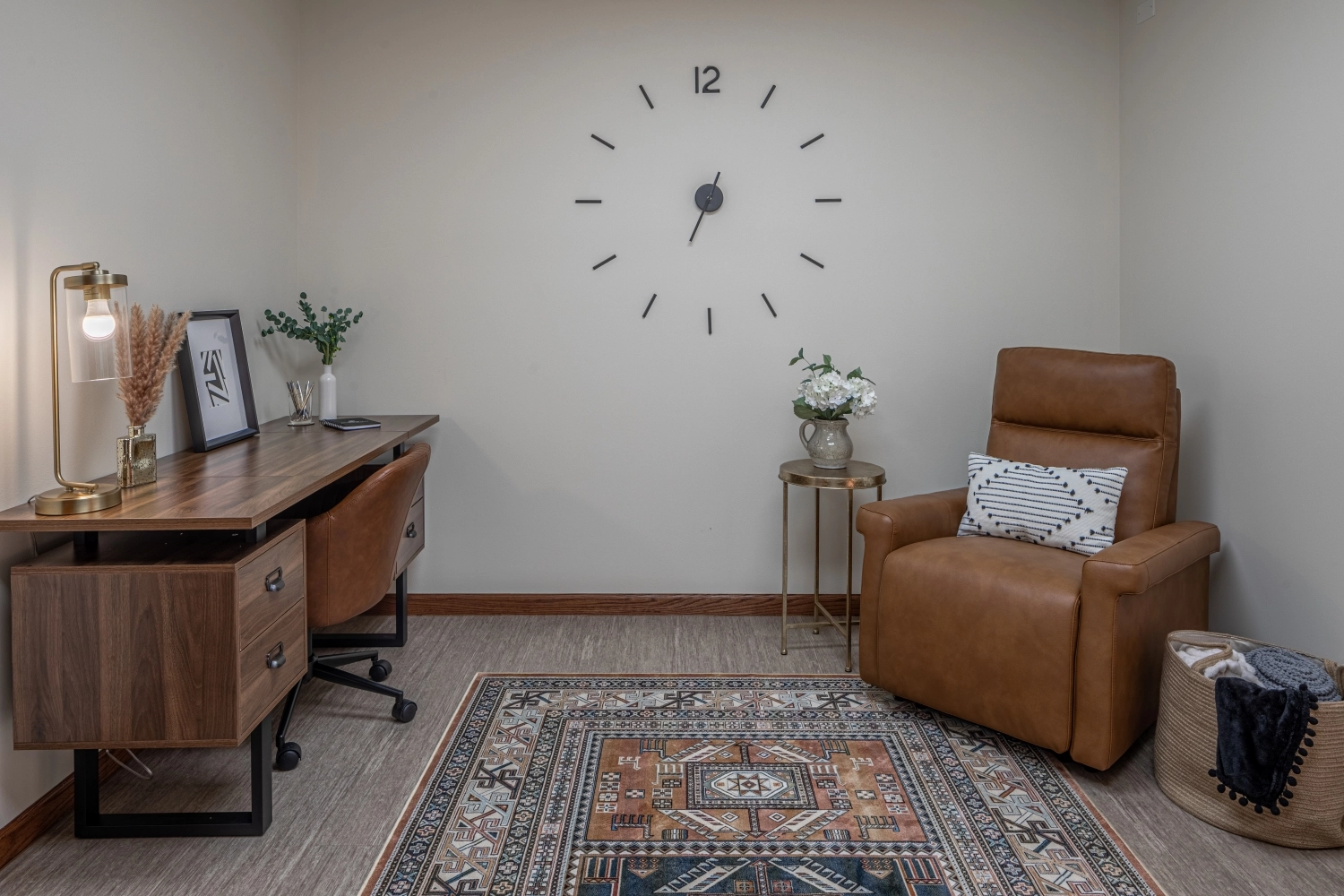 Consultation room with brown leather chair, wooden desk, geometric wall clock, and decorative rug