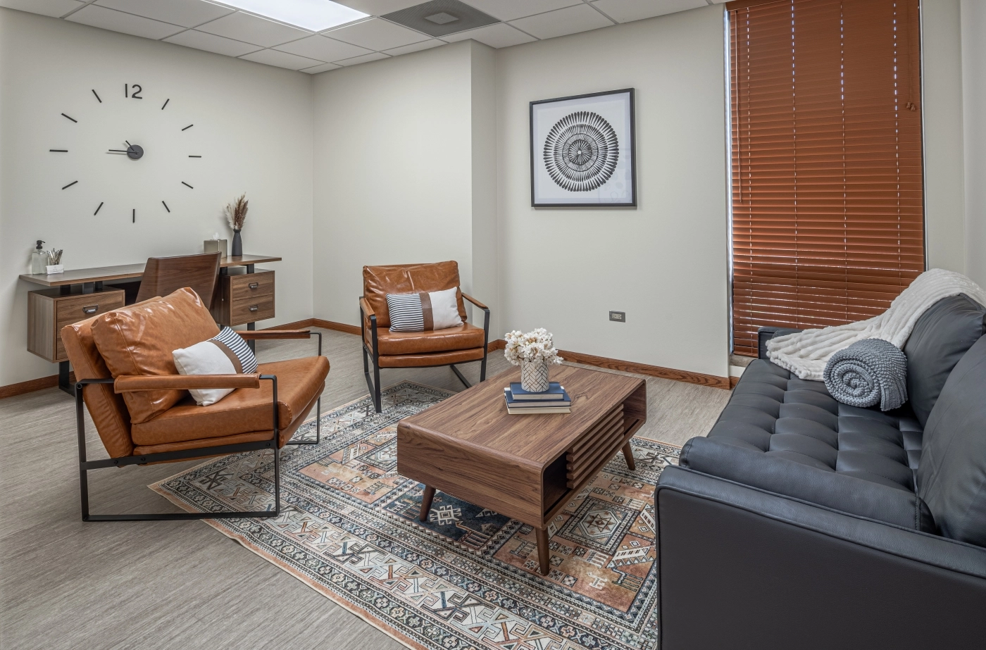 Comfortable waiting area with brown leather chairs, coffee table, clock, and framed artwork in a mental health clinic