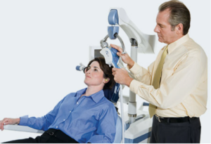 Clinician administering TMS treatment to patient seated in chair with magnetic coil device
