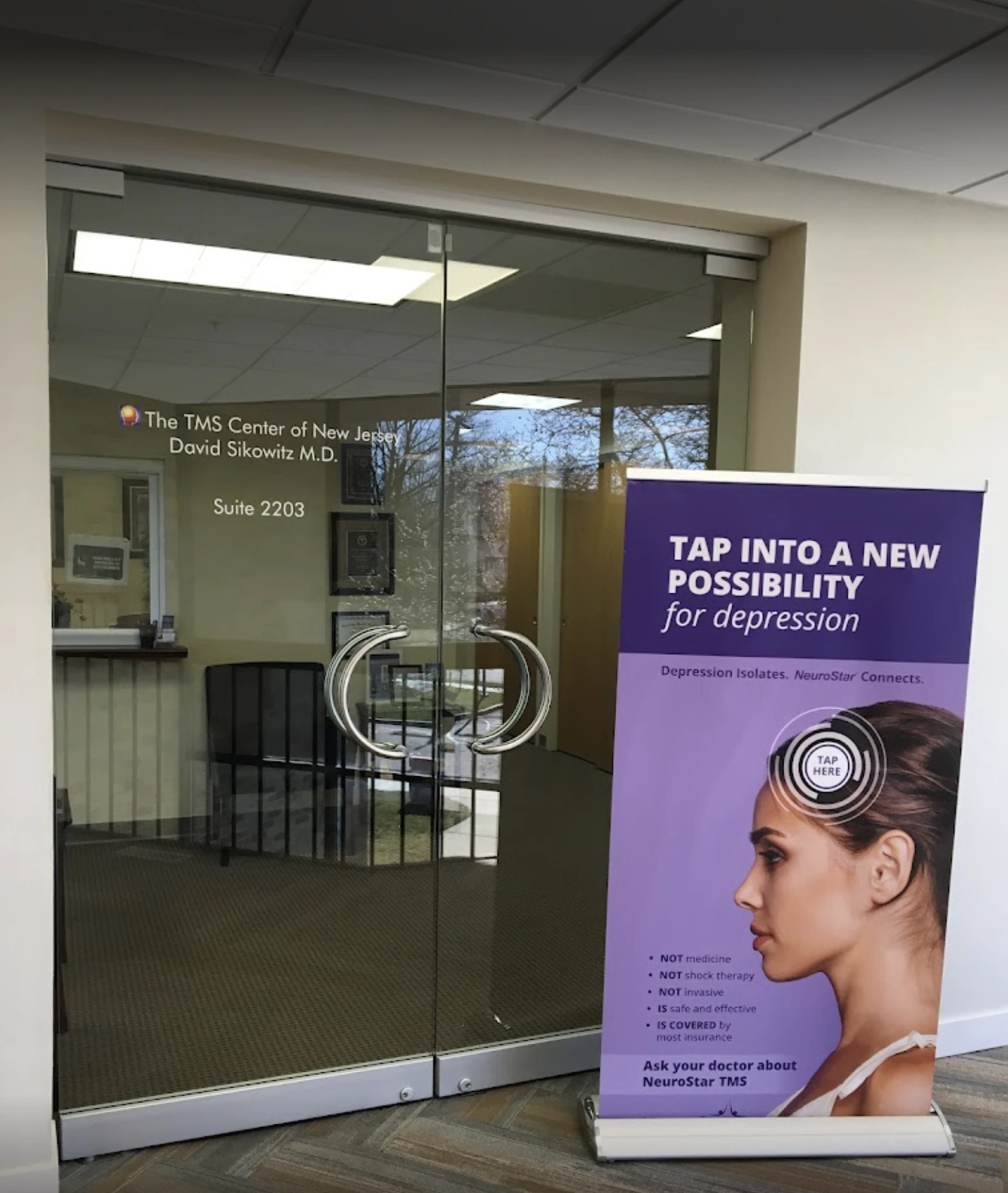 The TMS Center of New Jersey entrance, Suite 2203, with purple NeuroStar advertisement stating "TAP INTO A NEW POSSIBILITY for depression"