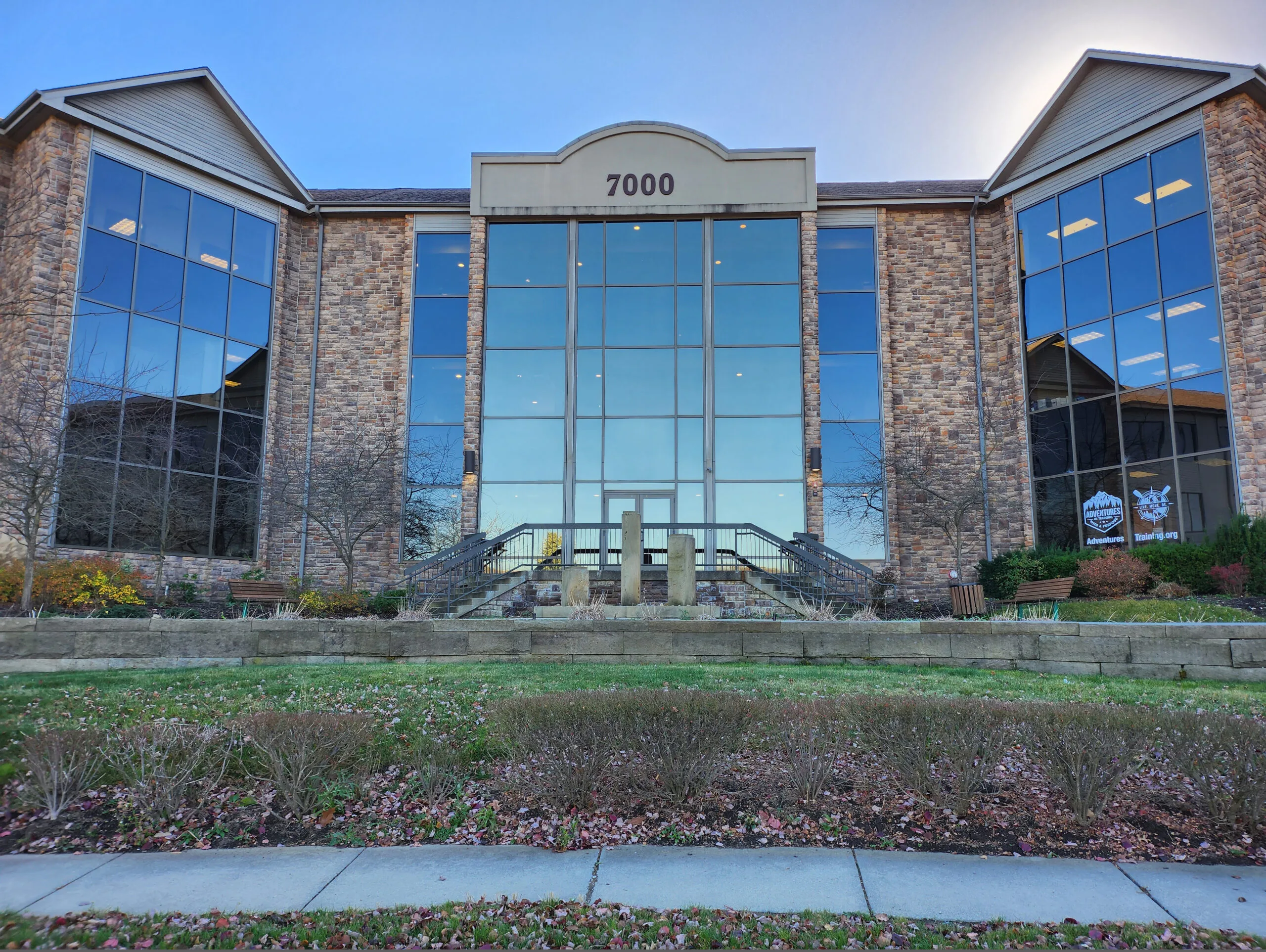 Stonewood clinic building exterior at 7000 with brick and glass facade, wide entrance with metal railings, and landscaped grounds