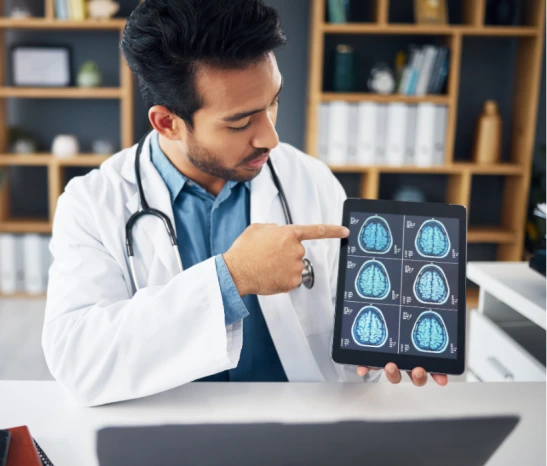 Doctor in white coat pointing to brain MRI scans on tablet