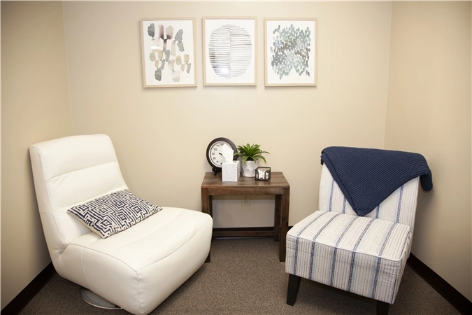 Consultation room with two comfortable chairs separated by small table and abstract wall art
