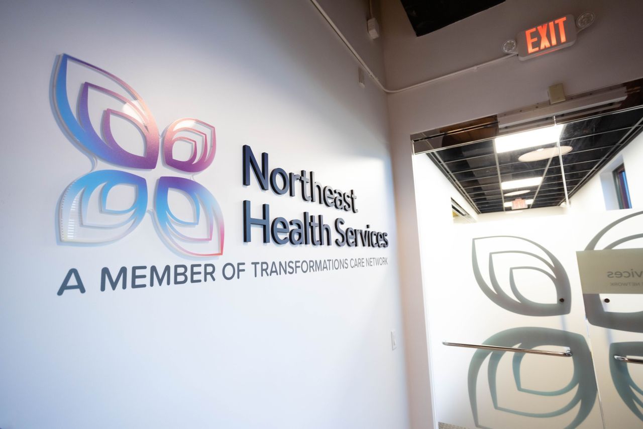 Northeast Health Services wall signage reading A Member of Transformations Care Network with colorful leaf logo