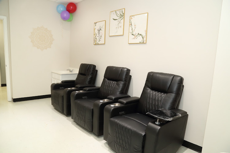 Modern clinic waiting room with three black leather recliners, botanical wall art, and decorative balloons