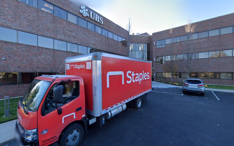 Red Staples delivery truck parked in front of a brick building with UBS signage