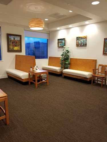 Clinical waiting room with wooden seating, pendant lighting, and framed artwork on walls