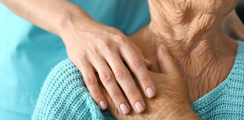 Caregiver's hand placed supportively on patient's arm during consultation