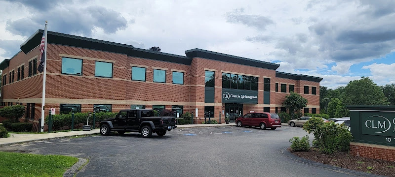 Center for Life Management brick building with CLM sign and parked vehicles in lot