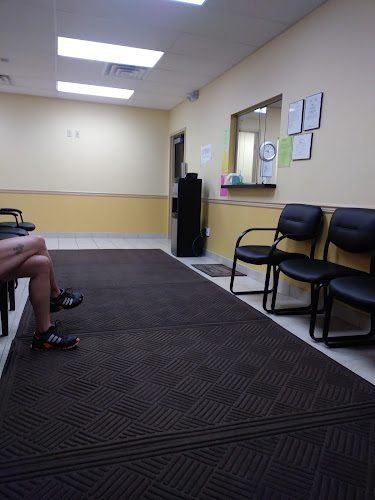 Charak Center for Health and Wellness waiting room with yellow and white walls, black chairs, and geometric patterned flooring