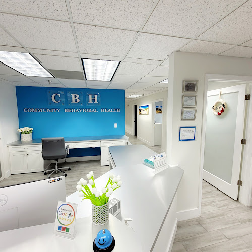 Community Behavioral Health reception area with blue branded wall, white desk, and framed credentials