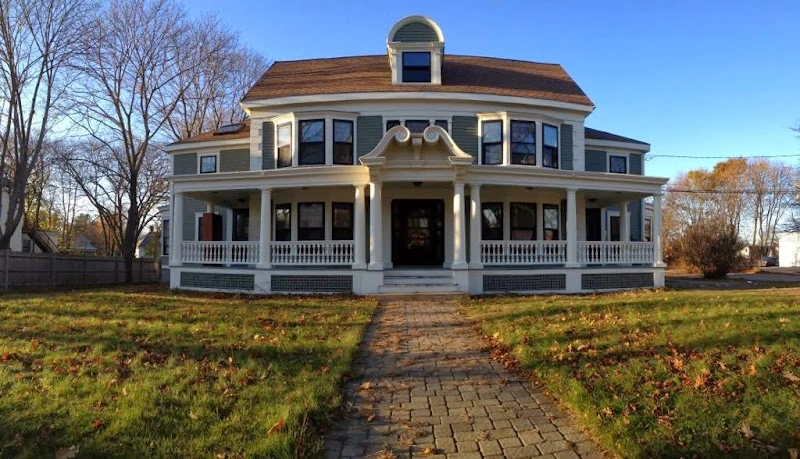 Two-story white colonial house with covered porch and brick pathway