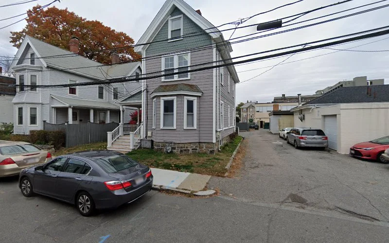 Multi-story residential houses on street with parked cars and fall foliage